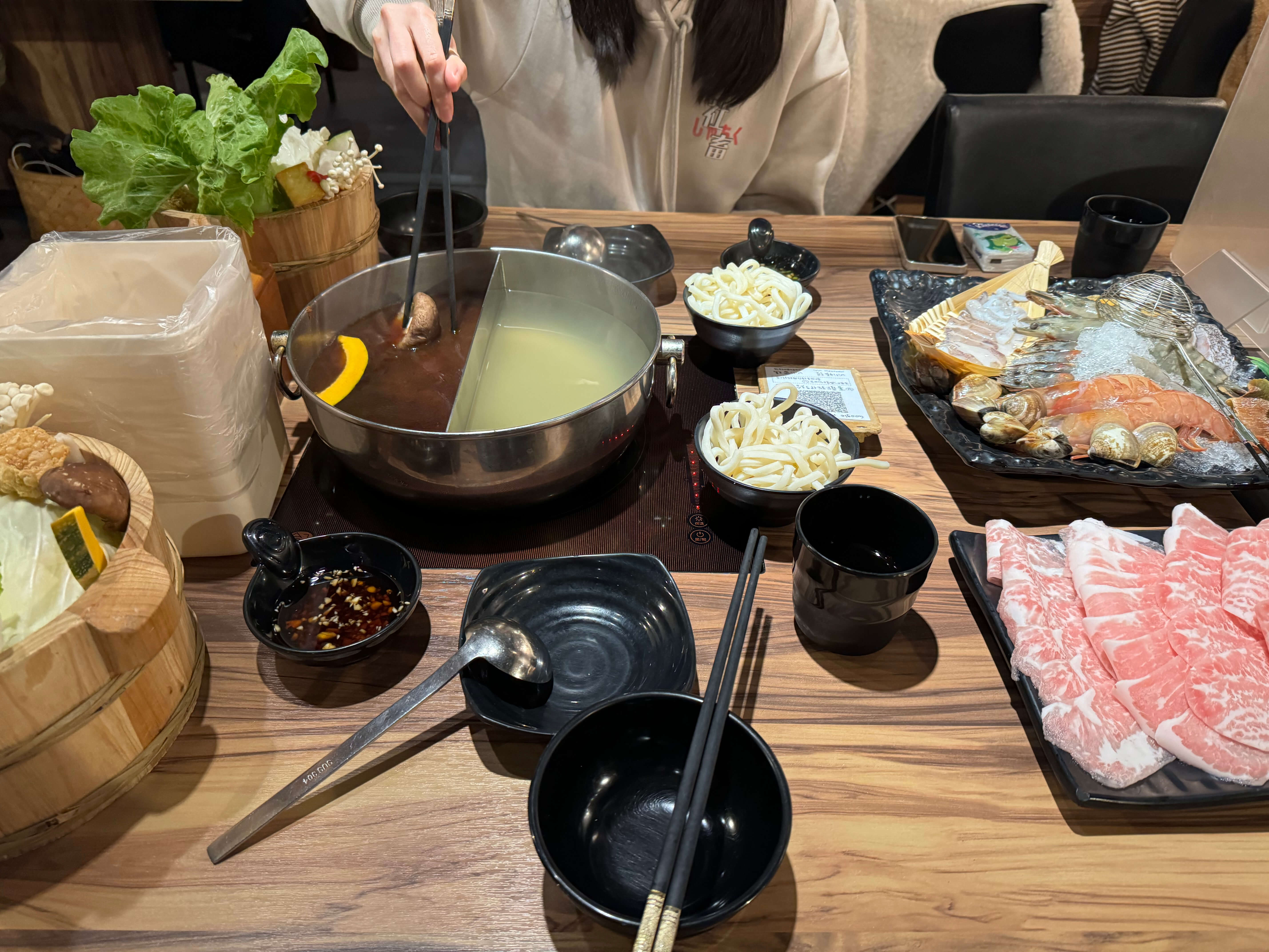 熱騰騰的火鍋擺滿了肉片、蔬菜和海鮮，看起來超級美味